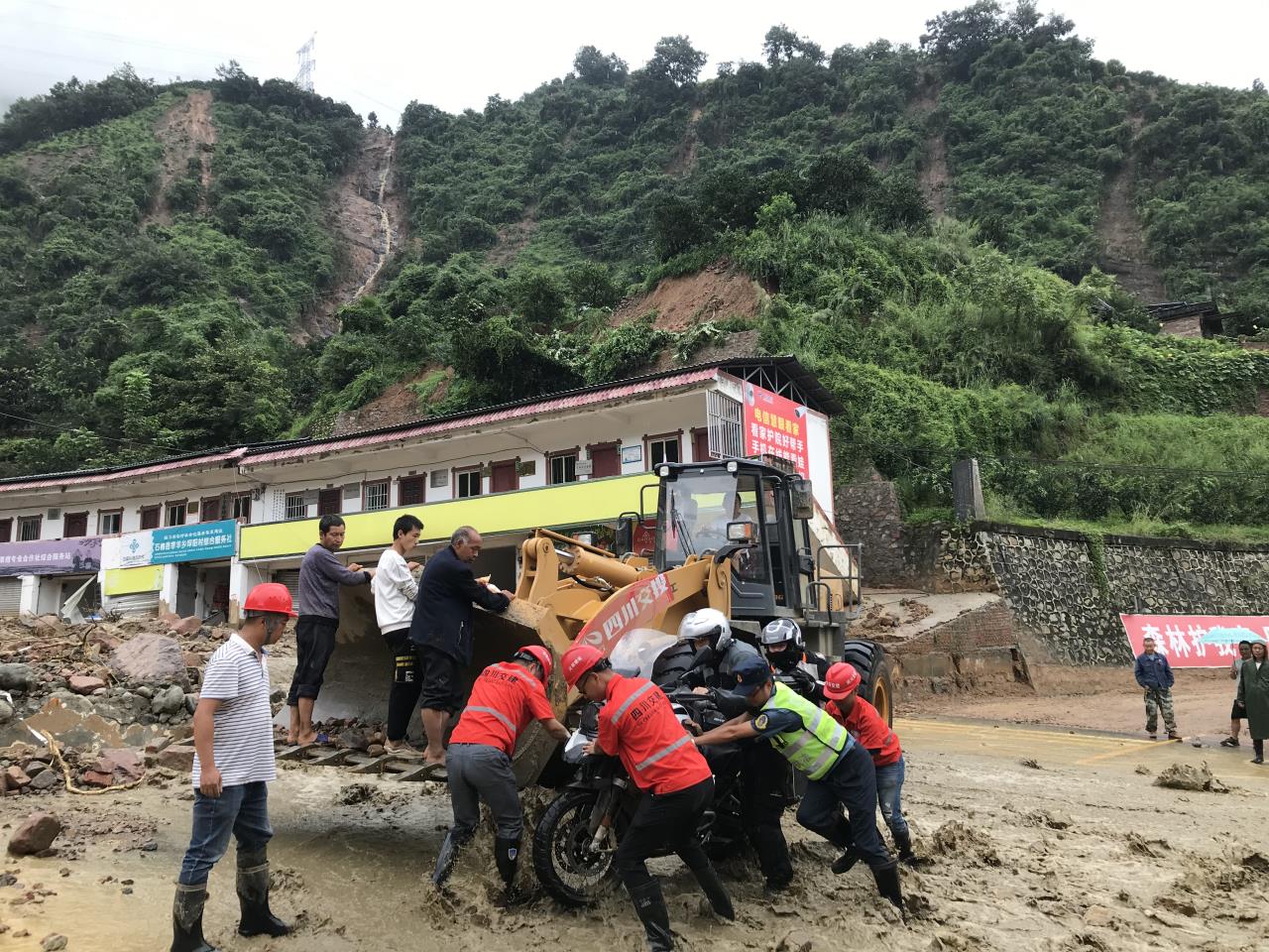8月18日，搶險人員與民警幫助被困群眾的摩托車通過涉水路面.jpg